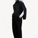 Front slanted view of black wool jacket on model wearing black pants, against a white background.