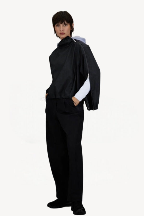 Front slanted view of black wool jacket on model wearing black pants, against a white background.