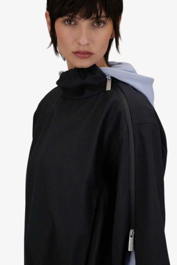 Side view of black wool jacket on model, against a white background.