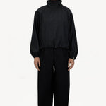 Front view of black wool jacket on model wearing black pants, against a white background.