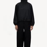 Front view of black wool jacket on model wearing black pants, against a white background.
