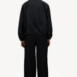 Back view of black wool jacket on model wearing black pants, against a white background.