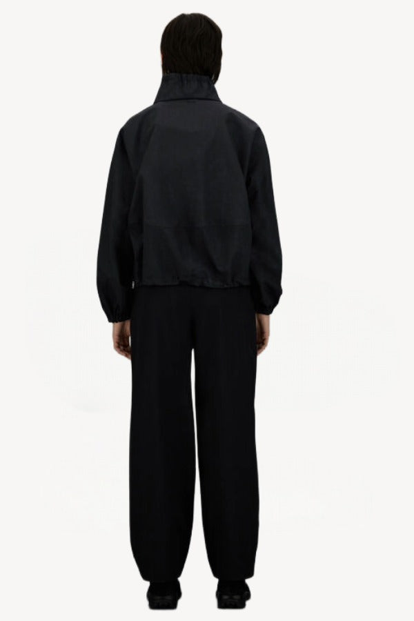 Back view of black wool jacket on model wearing black pants, against a white background.