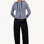 Front view of black laminar trousers on model wearing lilac top, against a white background.