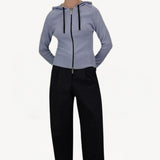 Front view of black laminar trousers on model wearing lilac top, against a white background.