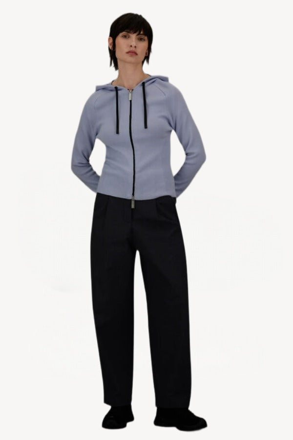 Front view of black laminar trousers on model wearing lilac top, against a white background.