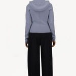 Back view of black laminar trousers on model wearing lilac top, against a white background.