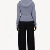Back view of black laminar trousers on model wearing lilac top, against a white background.
