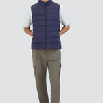 Front view of new blue gilet on model wearing green pants, white t-shirt and sneakers, against a white background.
