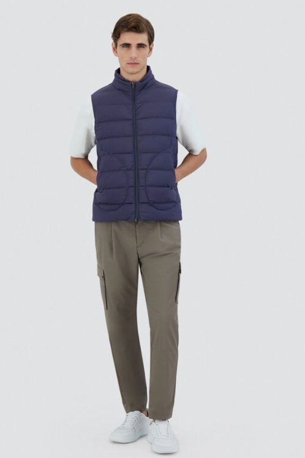 Front view of new blue gilet on model wearing green pants, white t-shirt and sneakers, against a white background.