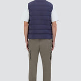 Back view of new blue gilet on model wearing green pants, white t-shirt and sneakers, against a white background.