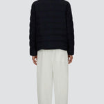 Back view of blue men's jacket on model wearing white pants and black sneakers, against a white background.