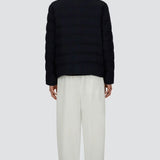 Back view of blue men's jacket on model wearing white pants and black sneakers, against a white background.