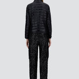 Back view of black bomber jacket on model wearing black t-shirt, trousers and mary janes against a white background.