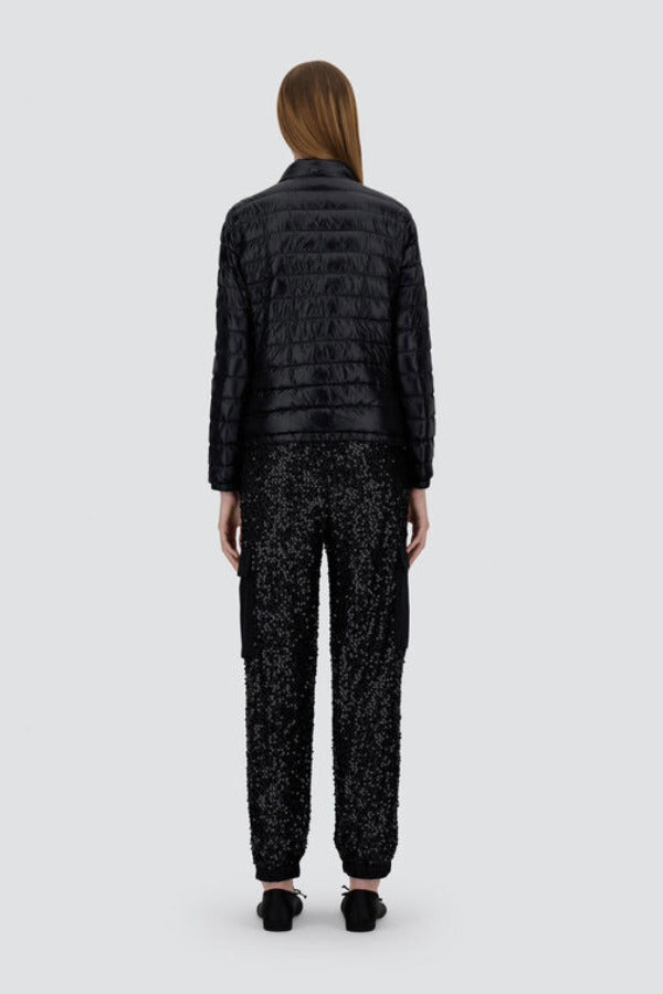 Back view of black bomber jacket on model wearing black t-shirt, trousers and mary janes against a white background.