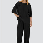 Front view of black pleated jersey t0shirt on model wearing black pants, against a white background.