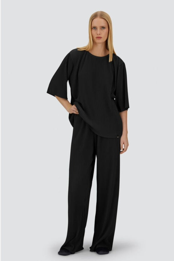 Front view of black pleated jersey t0shirt on model wearing black pants, against a white background.