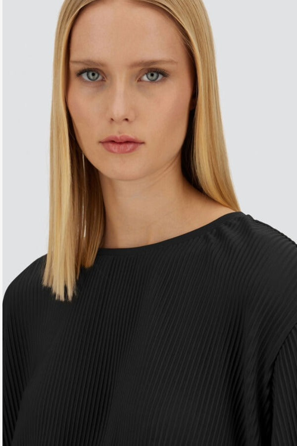 Front close up view of black pleated jersey t-shirt on model, against a white background.