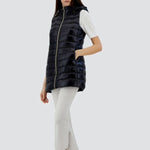 Front slanted view of black serena vest on model wearing white t-shirt, pants and sneakers, against a white background.