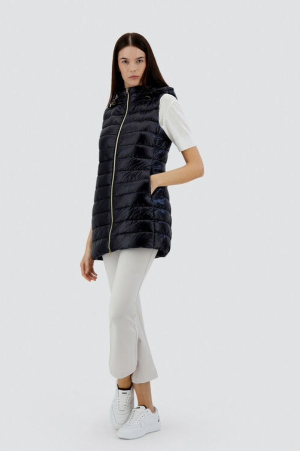Front slanted view of black serena vest on model wearing white t-shirt, pants and sneakers, against a white background.