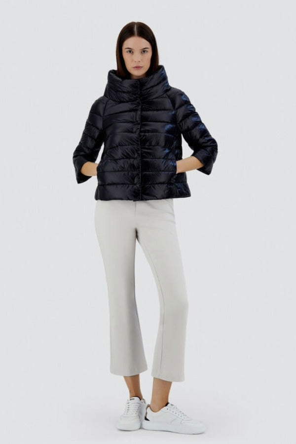 Front view of black sofia cape on model wearing white pants and sneakers, against a white background.