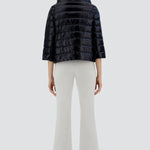 Back view of black sofia cape on odel wearing white pants and sneakers, against a white background.