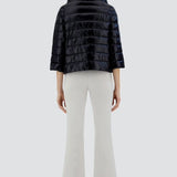 Back view of black sofia cape on odel wearing white pants and sneakers, against a white background.