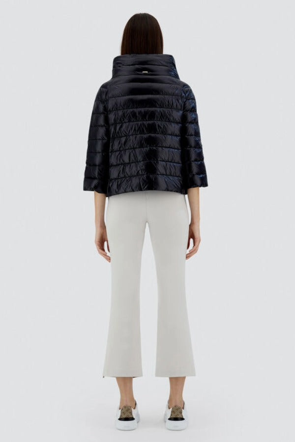 Back view of black sofia cape on odel wearing white pants and sneakers, against a white background.