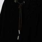 Front closeup view of black trousers on model, against a white background.