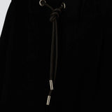 Front closeup view of black trousers on model, against a white background.