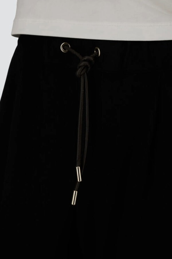 Front closeup view of black trousers on model, against a white background.