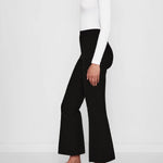 Side view of black geo kick pants on model wearing white t-shirt and flats, against a white background.