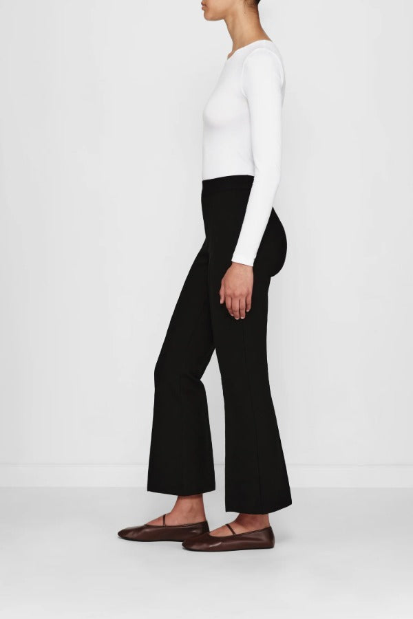 Side view of black geo kick pants on model wearing white t-shirt and flats, against a white background.