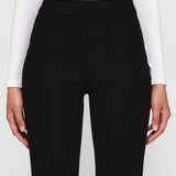 Front closeup view of black geo kick pants on model wearing white t-shirt, against a white background.