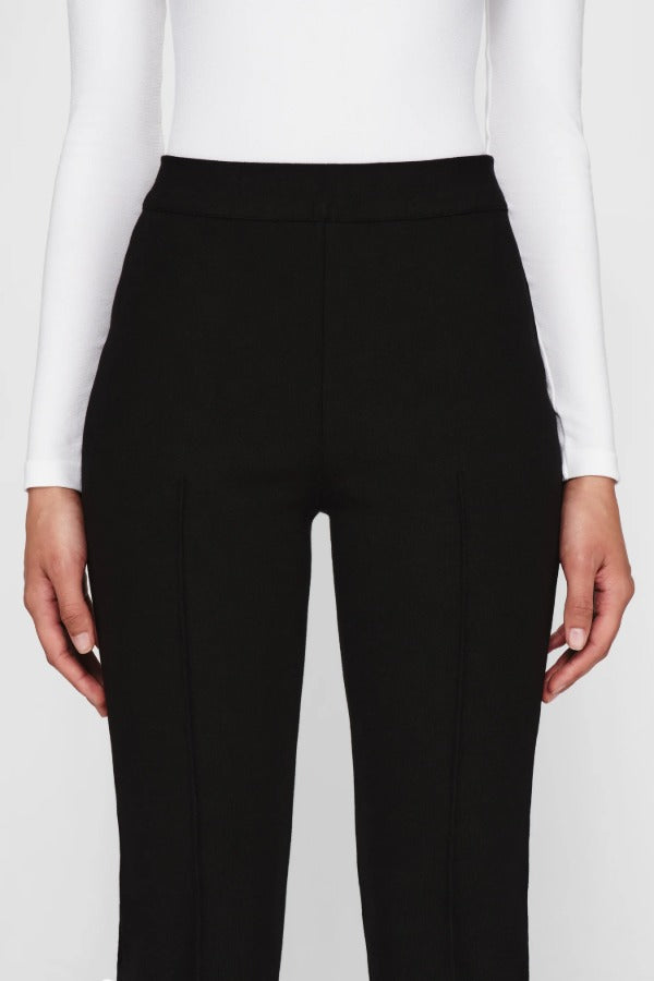 Front closeup view of black geo kick pants on model wearing white t-shirt, against a white background.