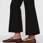Side closeup view of black geo kick pants on model wearing flats, against a white background.