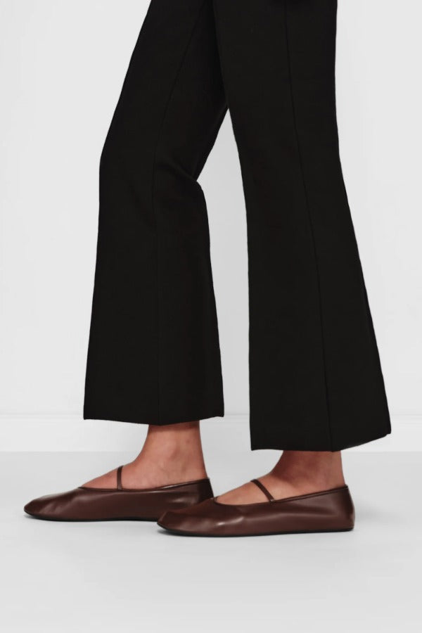 Side closeup view of black geo kick pants on model wearing flats, against a white background.