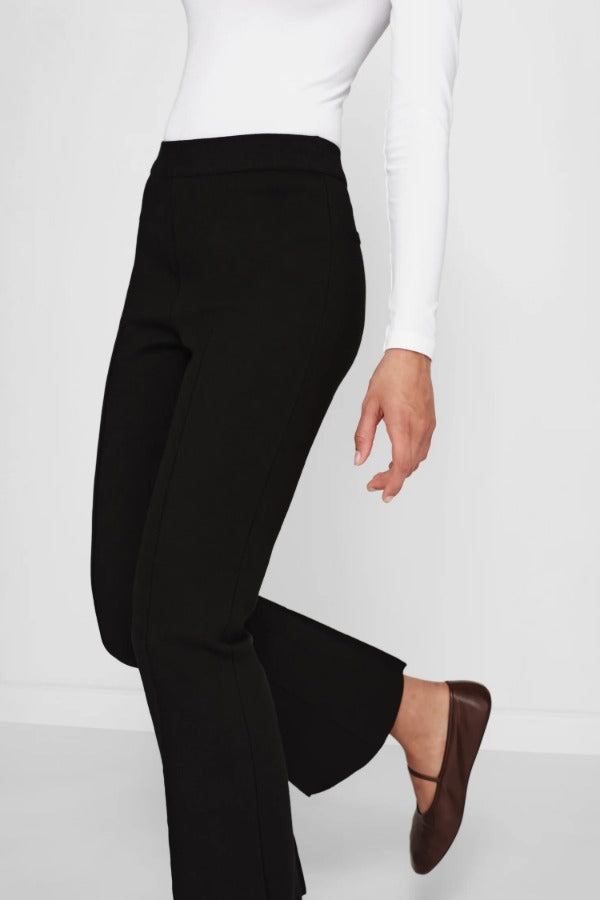 Alternate side view of black geo kick pants on model wearing white t-shirt and flats, against a white background.