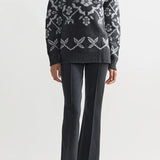 Front view of charcoal geo kick pants on model wearing a grey sweater and flats, against a white background.