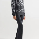 Alternate front view of charcoal geo kick pants on model wearing grey sweater and flats, against a white background.
