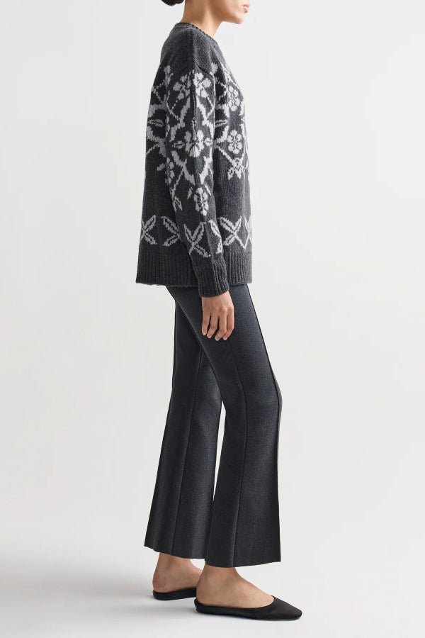 Side view of charcoal geo kick pants on model wearing grey sweater and flats, against a white background.