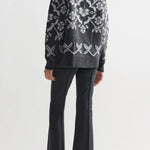 Back view of charcoal geo kick pants on model wearing grey sweater and flats, against a white background.