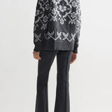 Back view of charcoal geo kick pants on model wearing grey sweater and flats, against a white background.