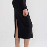 Side view of black geo petra skirt on model wearing black top and flats, against a white background.