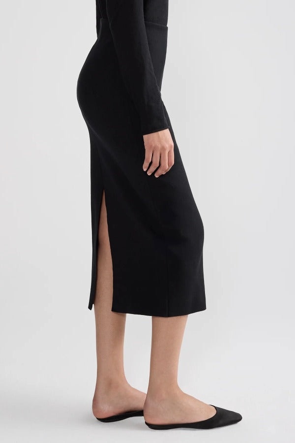 Side view of black geo petra skirt on model wearing black top and flats, against a white background.