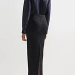 Back view of black lawton skirt on model wearing navy top and flats, against a white background.