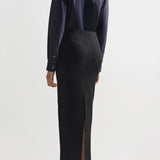 Back view of black lawton skirt on model wearing navy top and flats, against a white background.