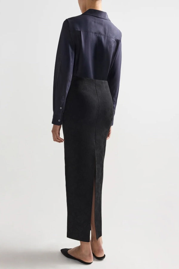 Back view of black lawton skirt on model wearing navy top and flats, against a white background.