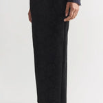 Side view of black lawton skirt on model wearing navy top and flats, against a white background.