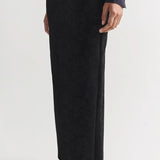 Side view of black lawton skirt on model wearing navy top and flats, against a white background.